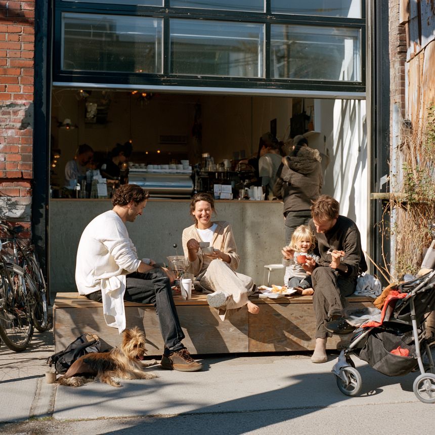 Two families sitting outside a café with a stroller and a dog