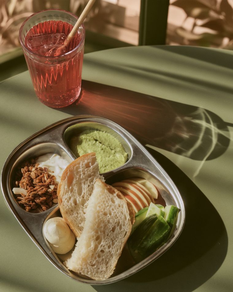 A child's meal tray with bread, hummus, fruit and granola